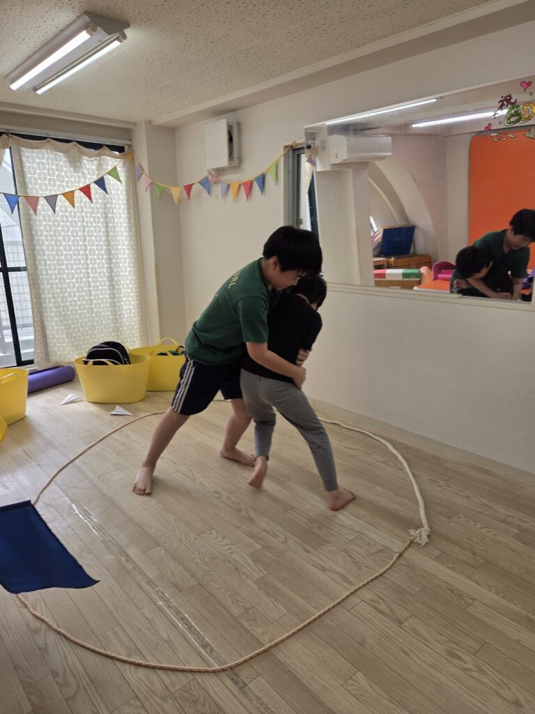 室内で相撲をとる男児たち。対格差はあるが思いっきり向き合い取り組んでいる