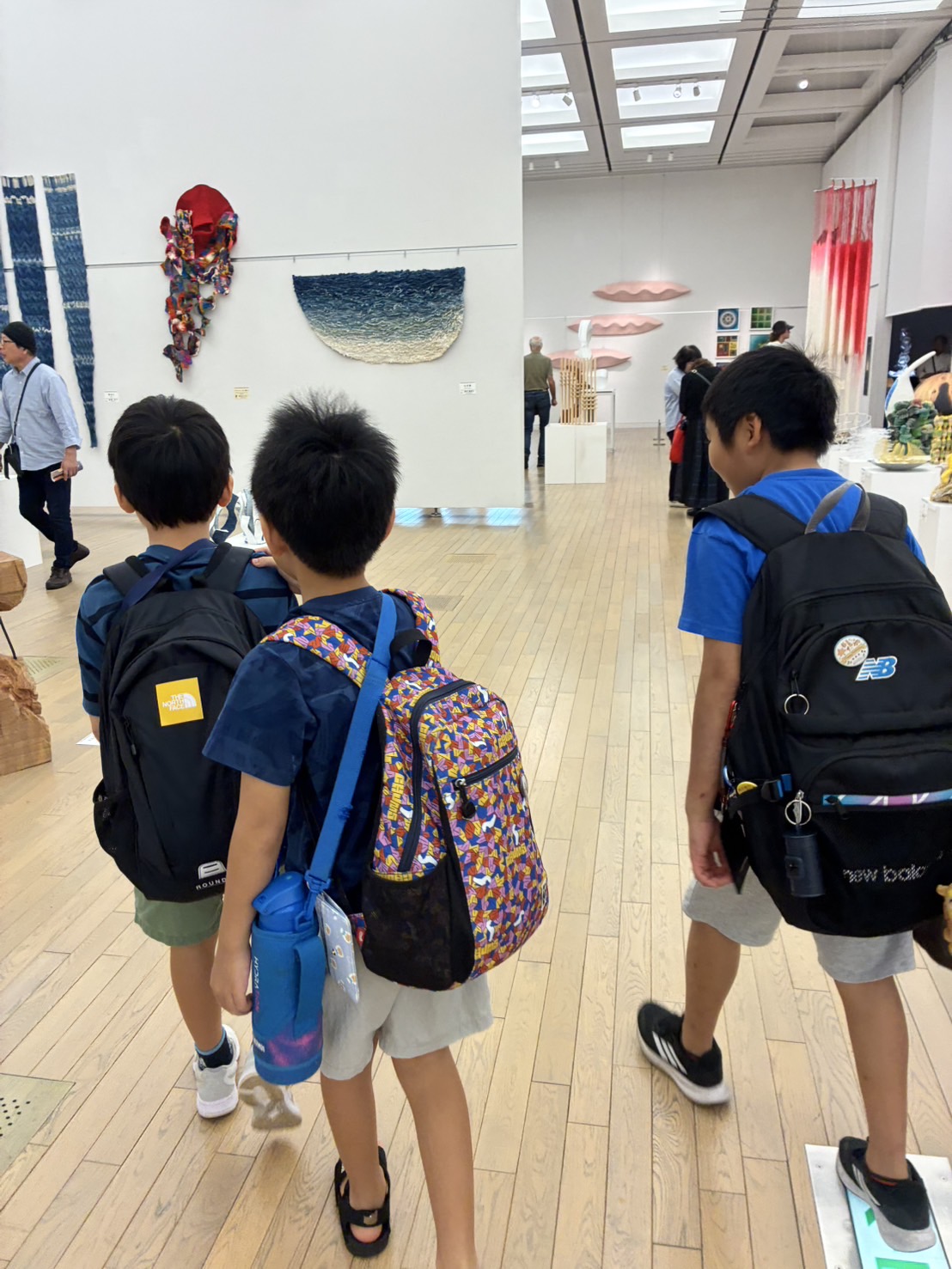 リュックを背負って展示を見に行く子どもたち