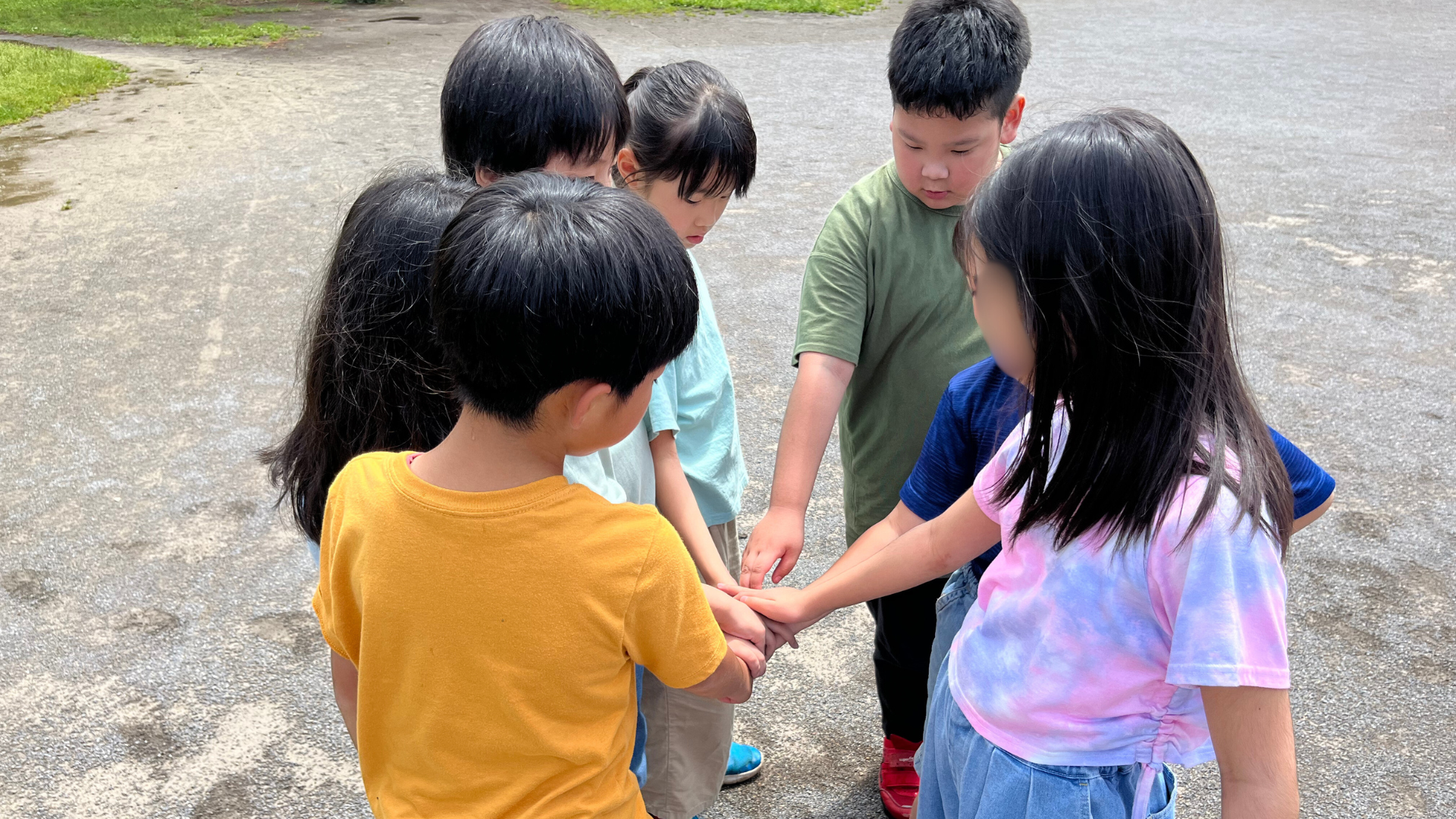 子どもたちが輪になって手を重ねる様子