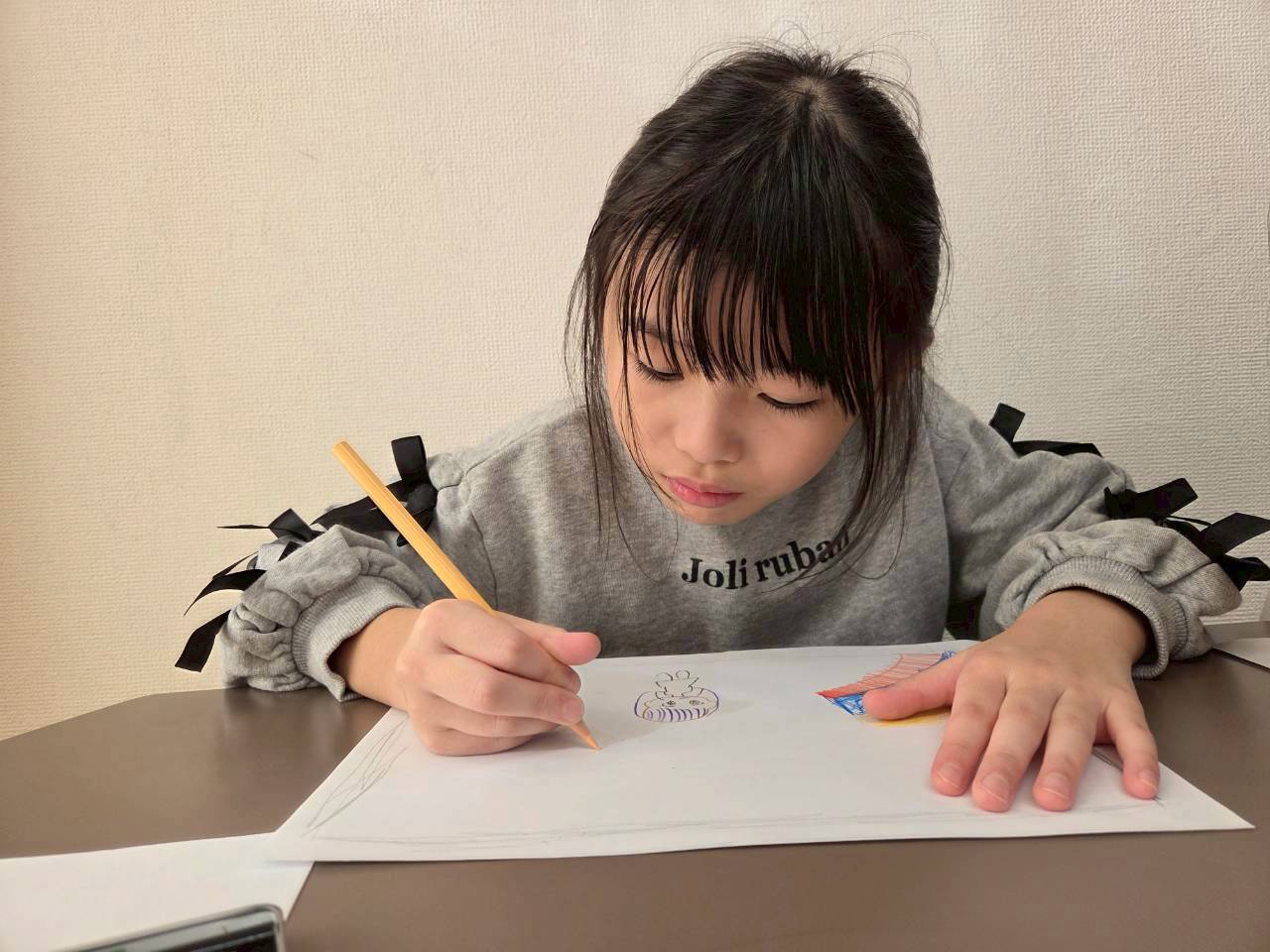 机に向かって鉛筆を動かす子ども