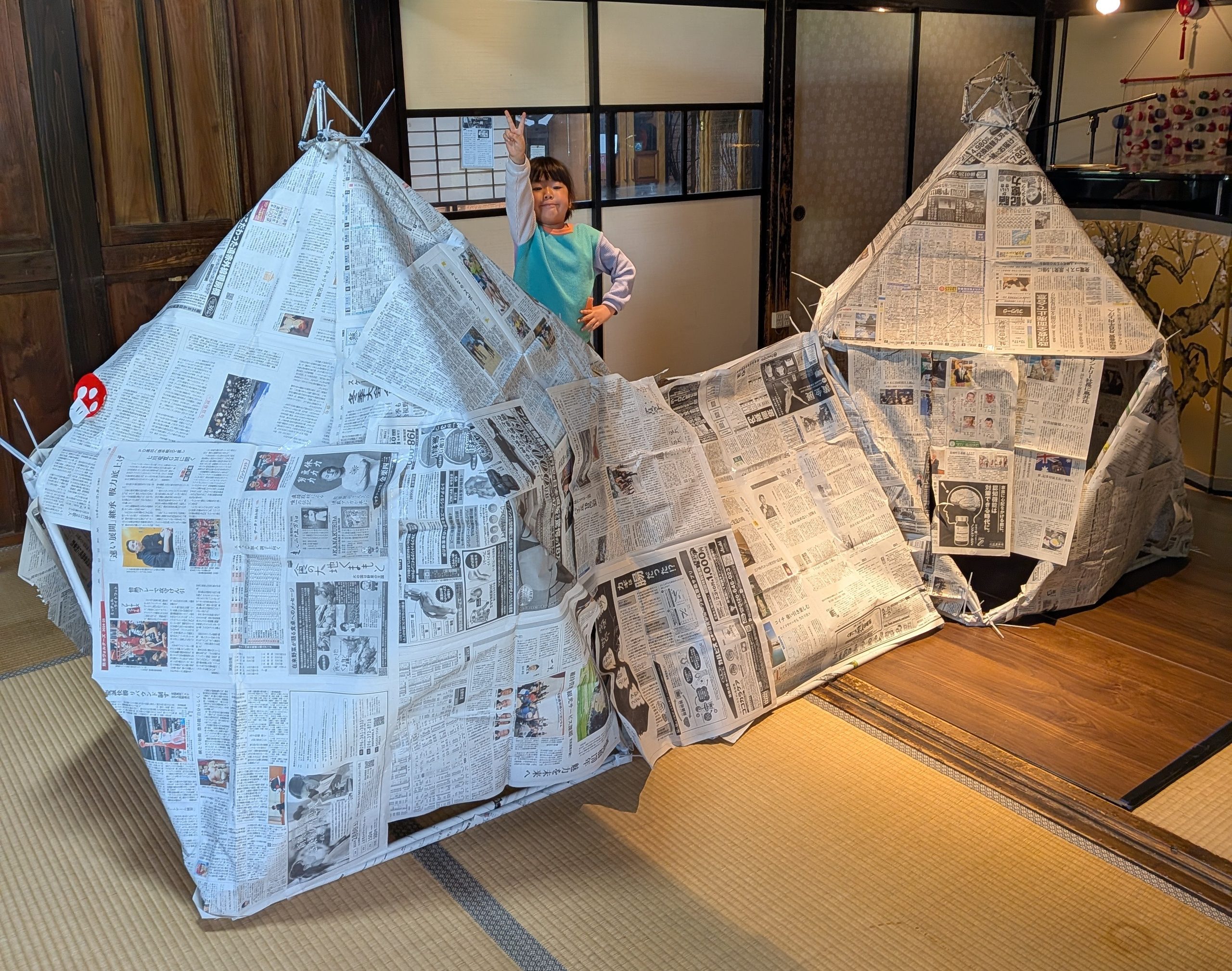 新聞紙でつくった大きな秘密基地の中にいる子ども