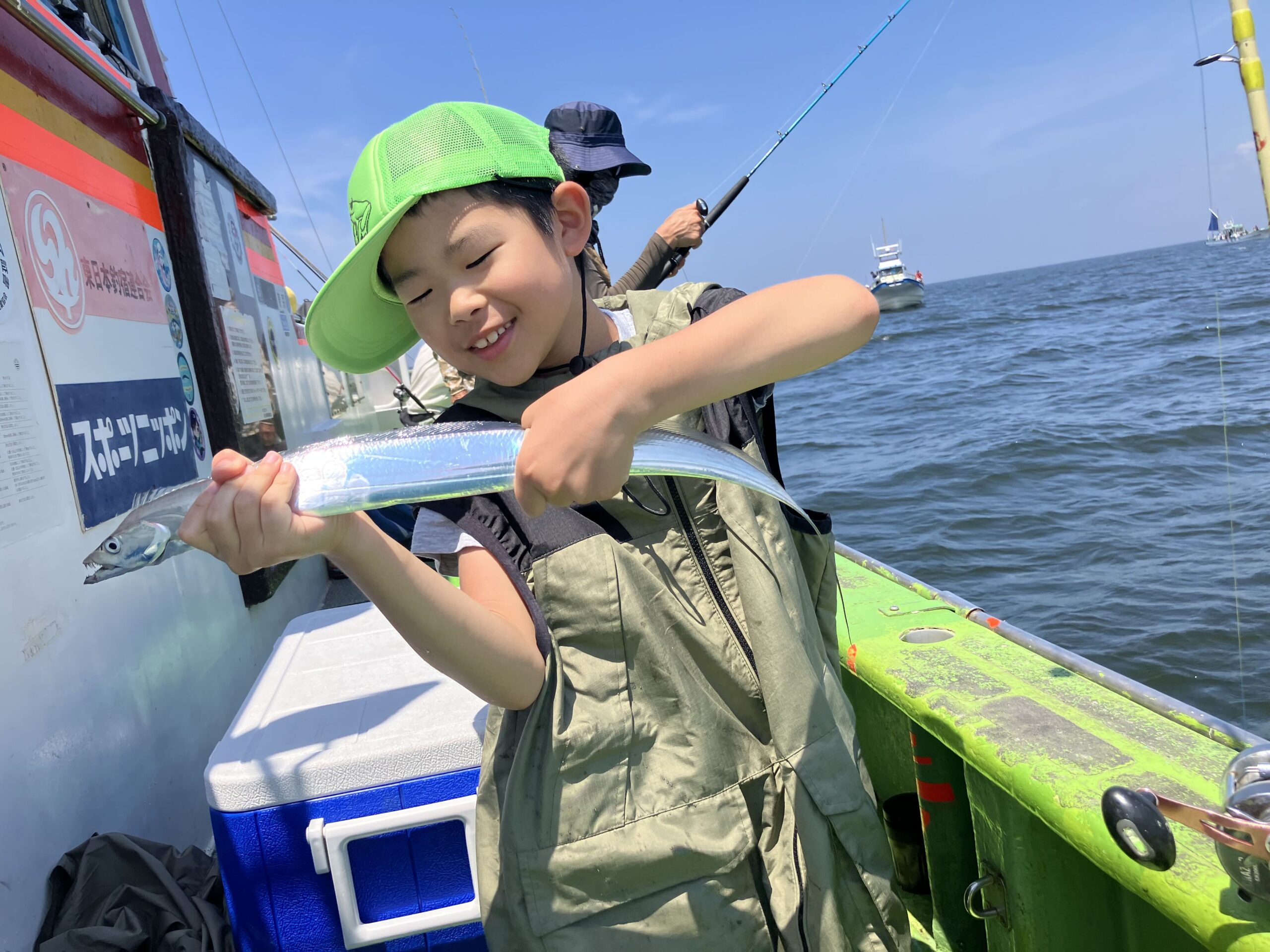 海辺で釣り上げた魚を手にする子ども