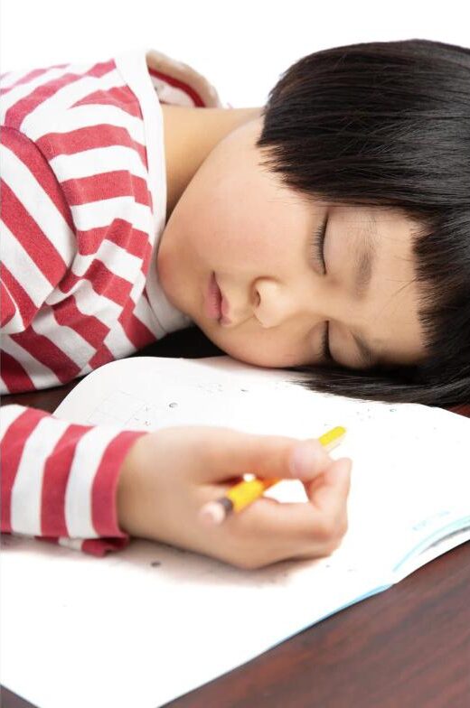 机に突っ伏して疲れた様子の子ども