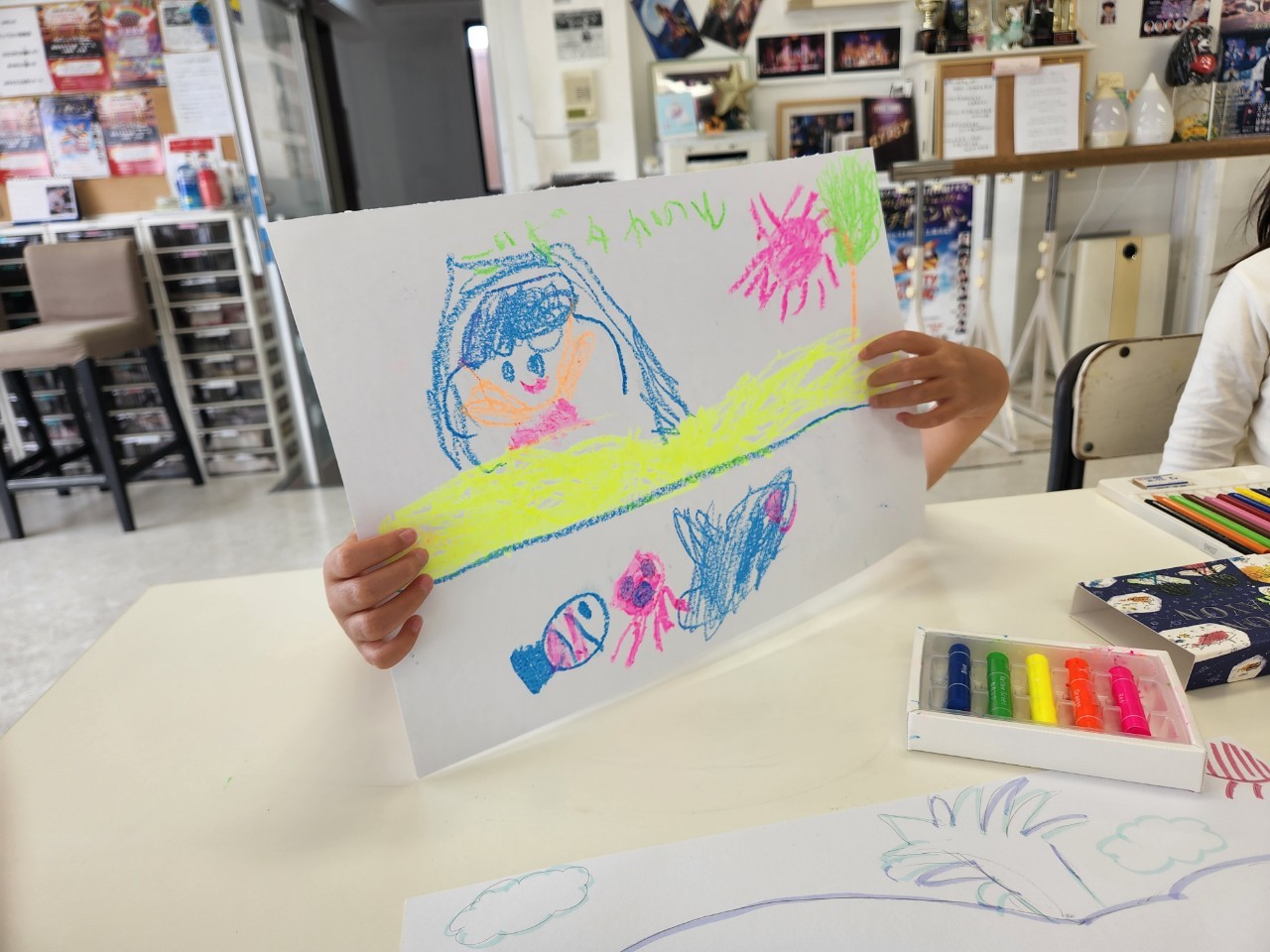 子どもが描いた絵と画材が並ぶ机