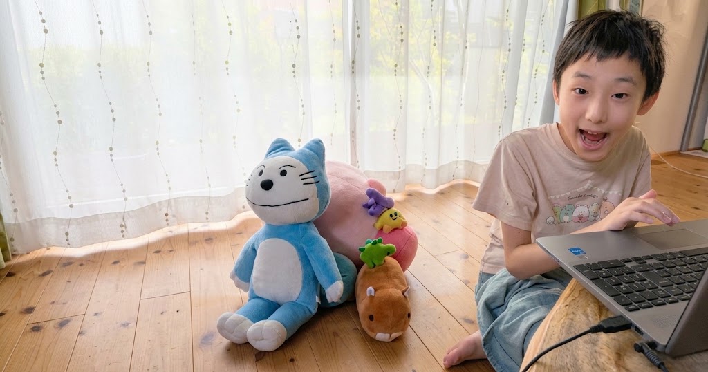 ノートパソコンの前で笑顔を見せる男の子