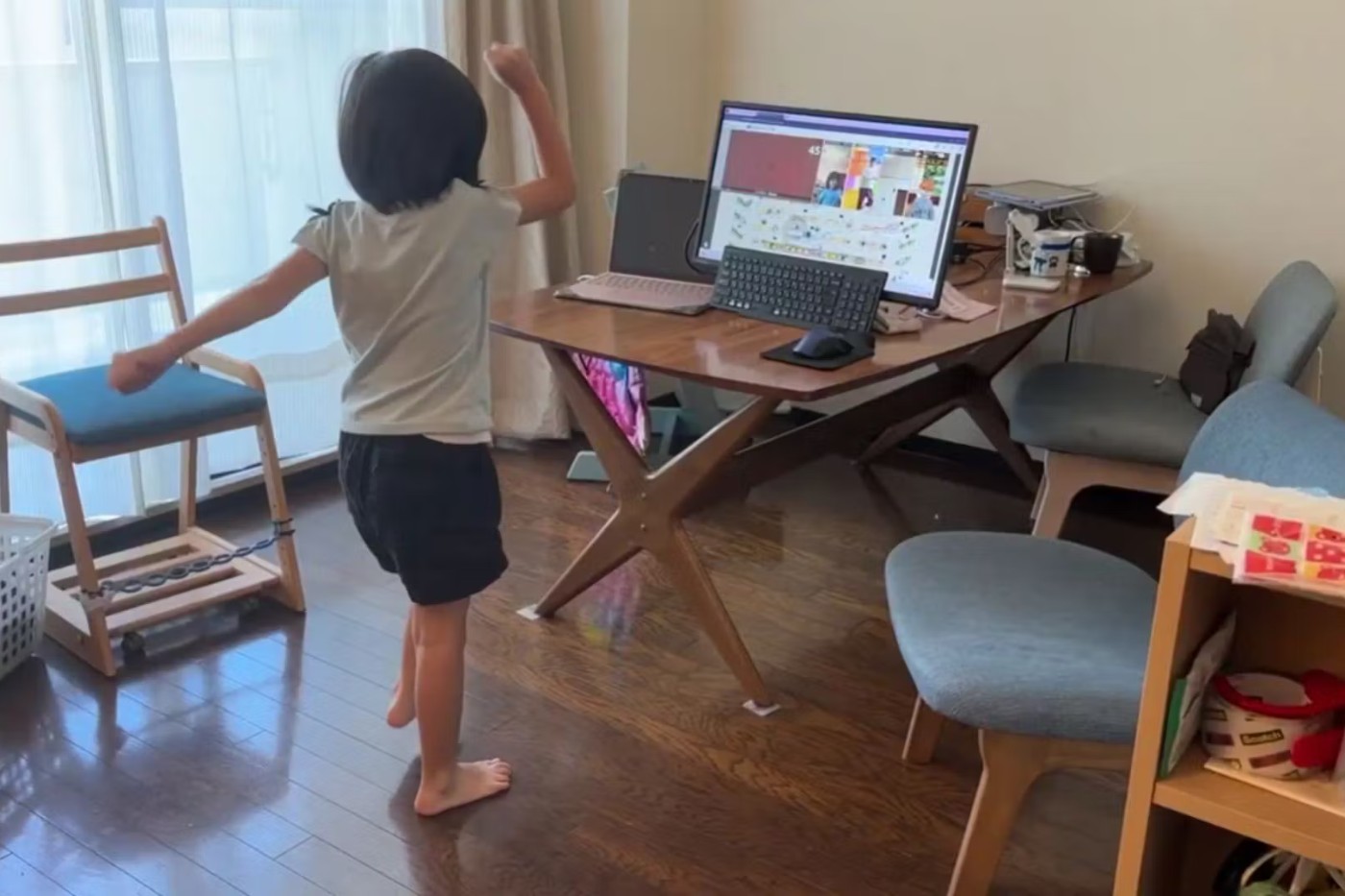 部屋でパソコンのそばを歩く子ども