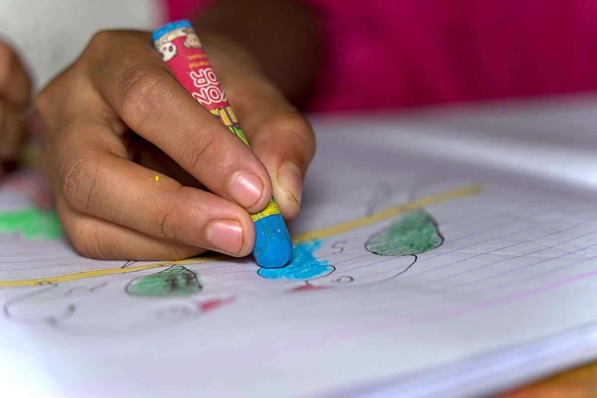 クレヨンで絵を描く子どもの手元